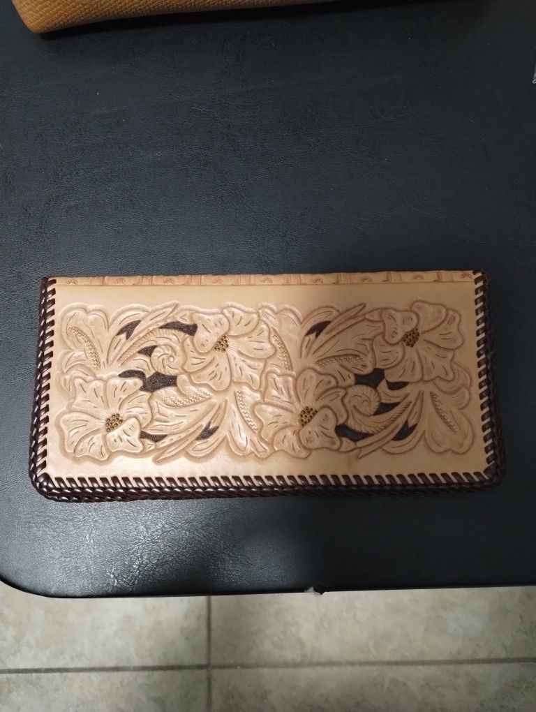 handcrafted, wallet or checkbook cover featuring a detailed floral tooling design on its exterior