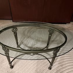 Oval glass top coffee table with ornate metal base