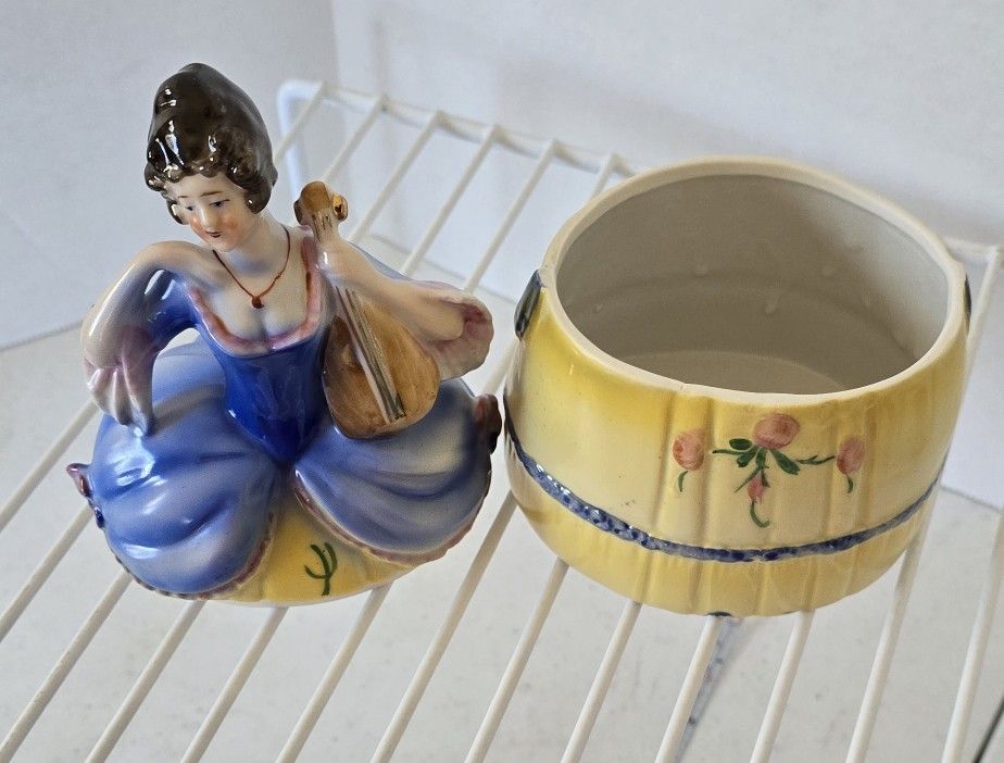 VTG Porcelain Trinket / powder box. Lady with yellow & Blue dress holding a chelo 