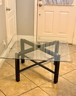 Contemporary square glass-top coffee table featuring a geometric, architectural dark wood or metal base- Southern Highlands Area /Vegas