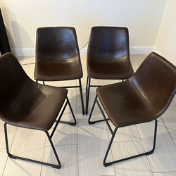 Four faux leather dining chairs with metal legs