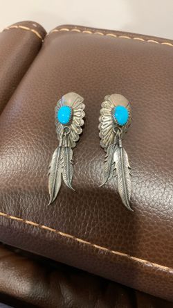 This is a pair of sterling silver and turquoise Native American Navajo feather dangle earrings