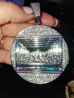 SILVER TONED PENDANT WITH THE LAST SUPPER SURROUNDED BY RHINESTONES.