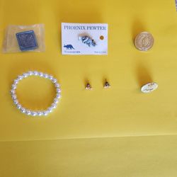 white faux-pearl stretch bracelet, a pair of pink bow-shaped stud earrings, and various pins or badges, $2 each