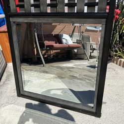 Black mirror in good condition, made of hardwood, measures 43 inches high and 34 1/2 inches wide