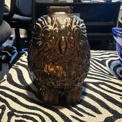 The Vintage Coin Bank 'Wise Old Owl' from the 1940s is a charming and collectible piece made of dark amber glass. Standing at 6 inches tall, this pigg