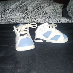 This is a pair of Jordan 6 Retro "UNC" toddler sneakers in university blue, white, and black leather. 