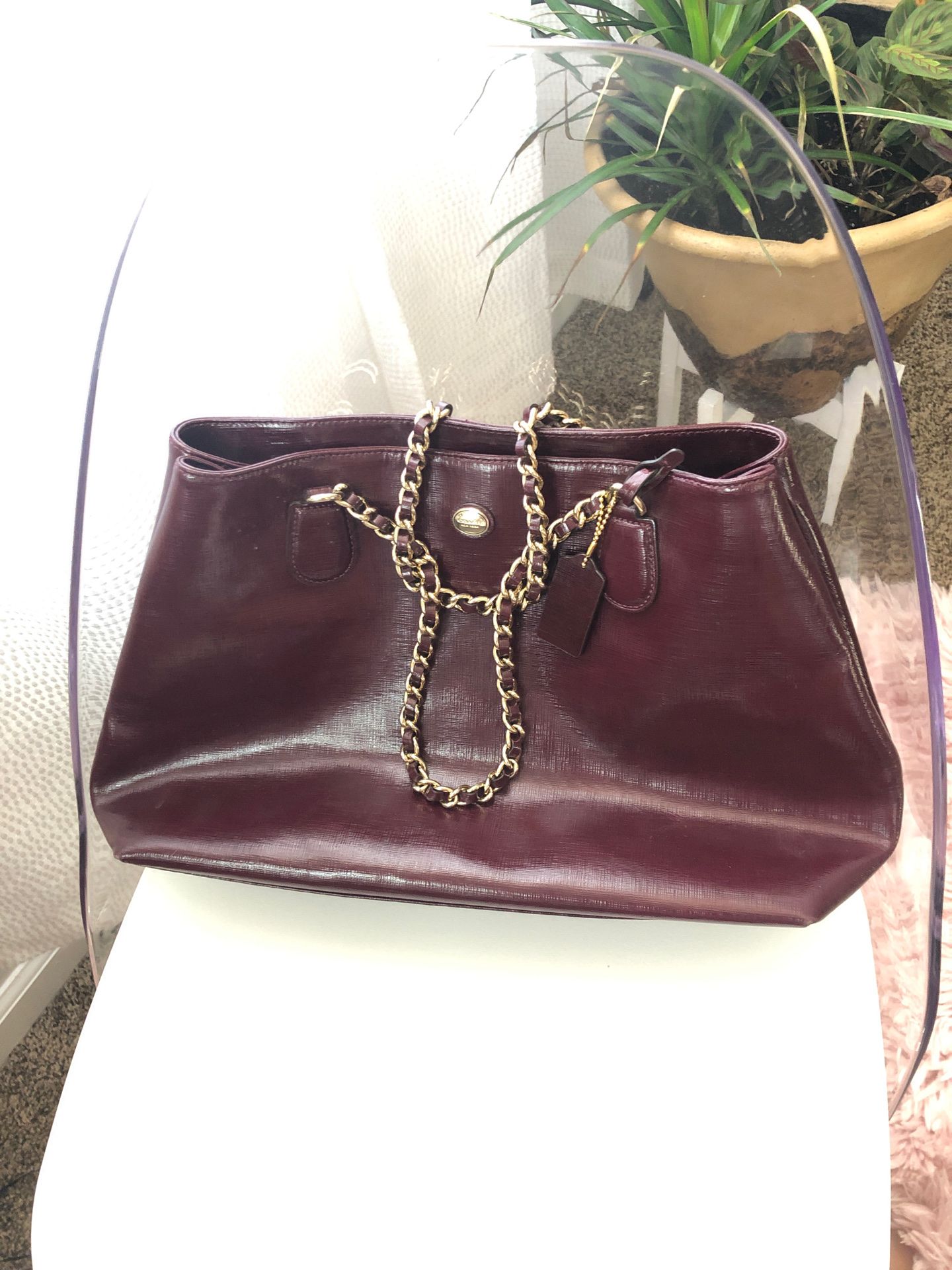 Shiny plum leather coach purse with gold chain.