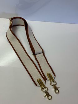 This is a Lily Jade crossbody bag strap in cream and brown with gold hardware.