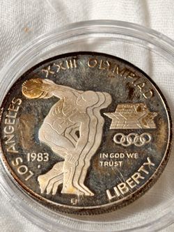 This is a 1983 United States $1 Proof Olympic Discus Commemorative Silver https://offerup.com/redirect/?o=RG9sbGFyLkl0 features a depiction of a tradi