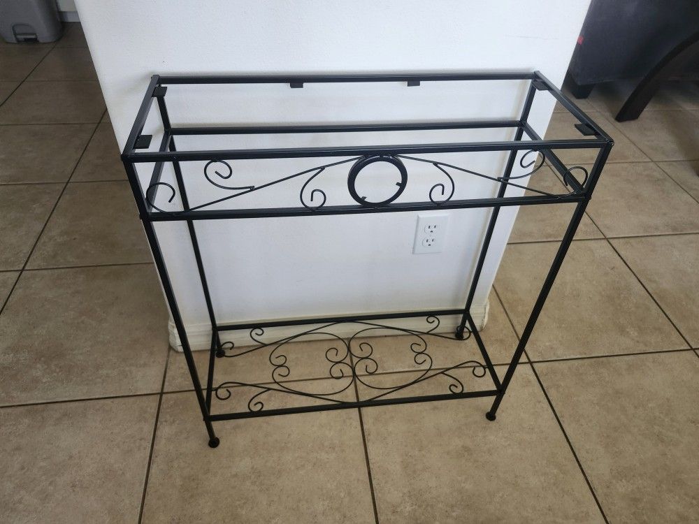 Decorative black metal plant stand with scroll design.