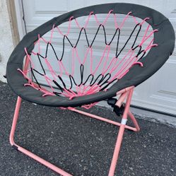 pink and black folding bungee chair with a metal frame. 
