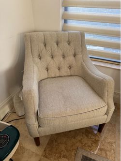Beige button-tufted accent chair in a beige fabric with dark espresso wood legs