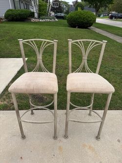 Textured metal counter-height bar stools feature a distinctive hourglass and fan-patterned backrest