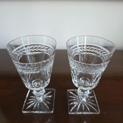 Pair of cut crystal wine or cordial glasses with decorative laurel band and starburst base, likely by Seneca Glass Company