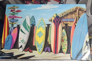 This piece is a "Surf Shack" tin sign featuring artwork