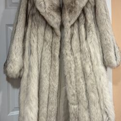 A long, full-length white fur coat made of natural white fox fur.