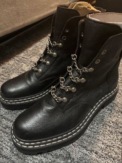 black leather combat-style,  fashion ankle boots with decorative chain hardware and thick contrast-stitched soles.