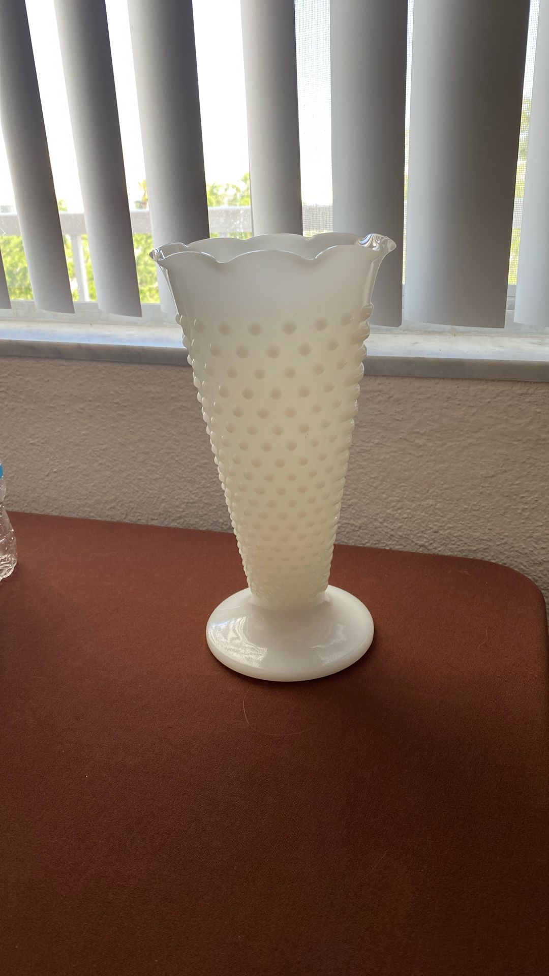 This is a piece of milk glass, specifically a hobnail vase.