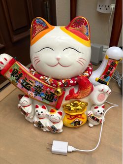 Ceramic Maneki Neko waving arm figurine, also known as a beckoning lucky cat