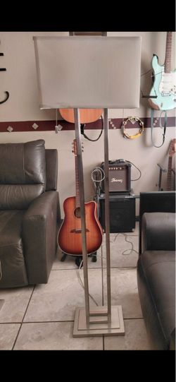 This brushed nickel double pole floor lamp features a modern design with a rectangular fabric shade.