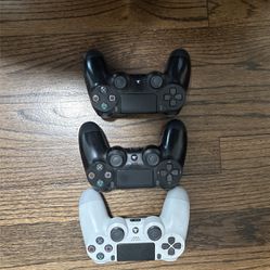 3 PS4 Controllers White, Black, And Black 