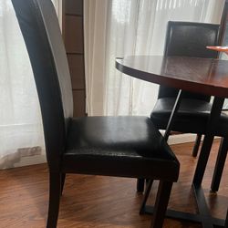 Round brown wooden table with 4 black leather dining chairs (Walker Edison)