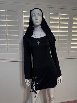 A sleek black long-sleeve mini dress with a fitted silhouette. Features lace-up grommet detail at the hem for an edgy finish. Lightweight, stretch fab