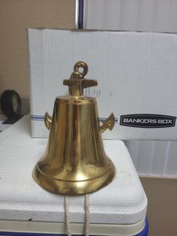 Vintage solid brass nautical ship's bell equipped with a matching anchor-shaped wall-mounting bracket.