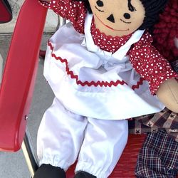handmade rag doll, likely inspired by the classic Raggedy Ann character, distinguished by its black yarn hair and embroidered face.  Type: Traditional