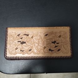 handcrafted, wallet or checkbook cover featuring a detailed floral tooling design on its exterior