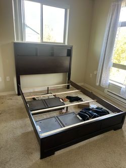 Queen sized, dark brown bed frame with shelving on headboard