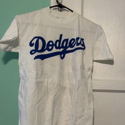 Classic white t-shirt featuring bold blue "Dodgers" script across the chest. Soft cotton look. Simple, sporty style. Great for game days or casual   M
