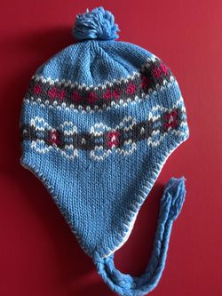 Blue knit hat with Fair Isle design, earflaps, and pom-pom for children