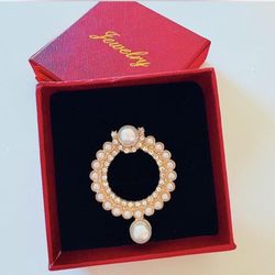 Gold-tone pearl l brooch with sparkling cubic zirconia details.