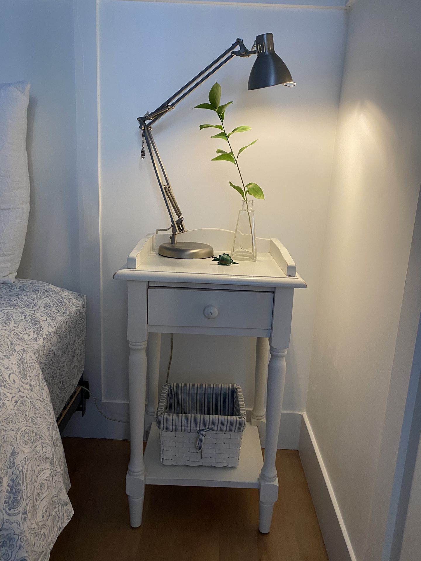 Pre-owned solid wood off white finish table with one drawer, scalloped edge on top and a lower shelf with a removable stripe lining basket.