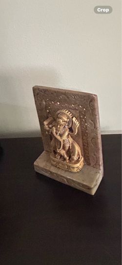 decorative stone and resin figurine, resembling a depiction of the Hindu deity Krishna as the butter thief, mounted on a carved soapstone base.
