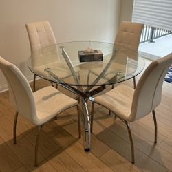 A Round Dining Table With 4 White Chairs.