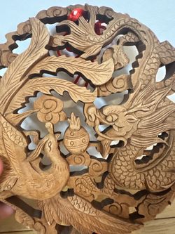 This is a traditional, hand-carved circular wooden wall plaque