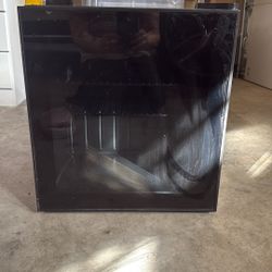 Small black mini fridge with a glass door, blue LED light from inside