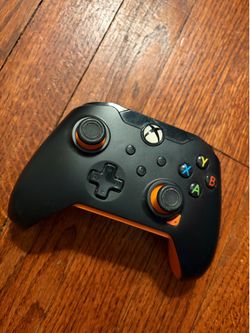 Black Xbox controller with orange accents on the grips and thumbsticks