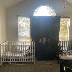 White crib and black toddler bed with mattress