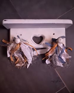 Rustic, white-painted wooden wall hook rack featuring a central heart-shaped cutout and decorated with nautical-themed fabric tassels