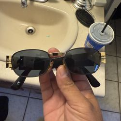 This is a pair of vintage Gianni Versace Mod S73 or S72 sunglasses in black with gold-tone Medusa medallions. 