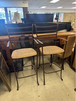 Pair of wrought iron bar stools with tan woven seats
