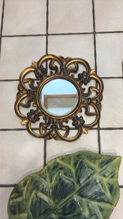 Gold wall mount mirror, gold frame picture of a bathtub, metal, green leaf, three candle holders, decorative, and a wooden golden tray