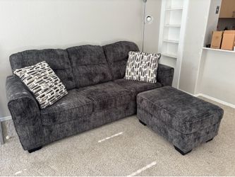 Gray three seat couch with matching pillows and ottoman