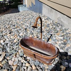 oval-shaped metal planter, brown finish, attached decorative spigot handle