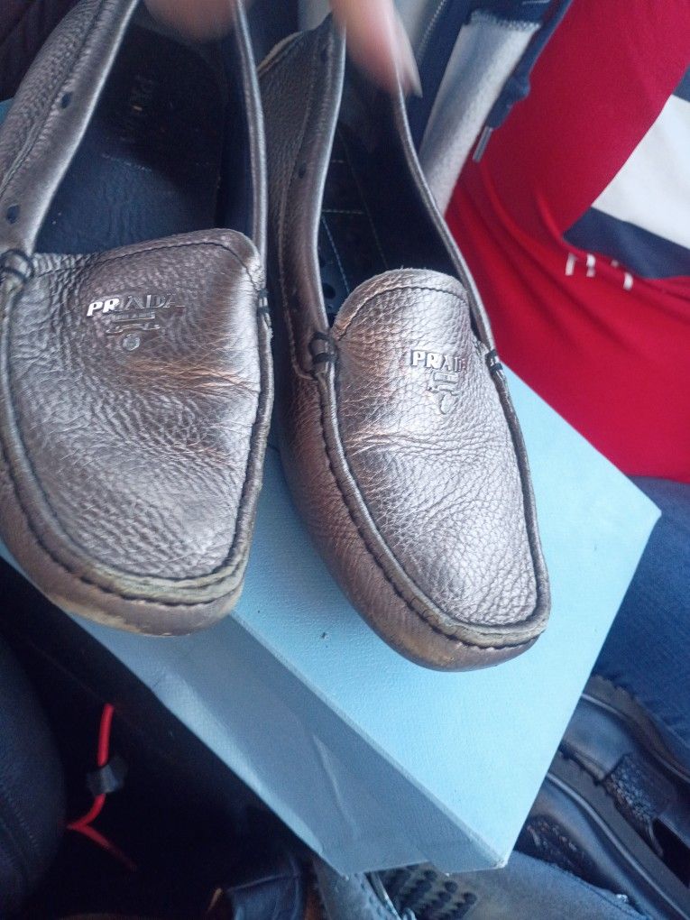 This is a pair of metallic silver Prada leather driving moccasins.