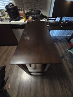 Dark brown counter top high bar table with stools.